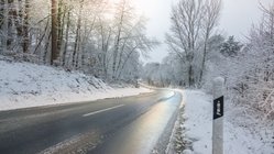 Winterliche Straße mit glänzenden Stellen.