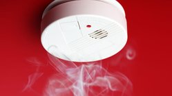 Rauchmelder an einer rot gestrichenen Decke mit Rauchschwaden