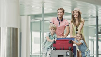 Familie mit Koffern am Flughafen.