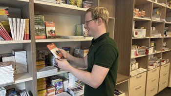 Mann holt einen Reiseführer aus einem Regal