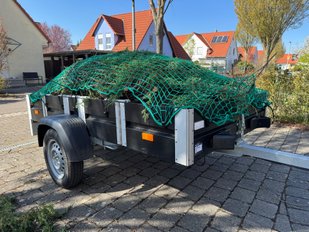 Faltos-Anhänger steht mit Netz für Grüngut in einer Einfahrt. 