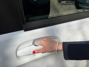  Frau öffnet Bügeltürgriff. 