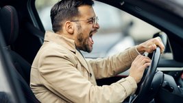 Wütender Mann sitzt im Auto und drückt auf die Hupe. 