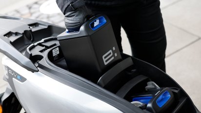 Eine Frau zieht einen Akku des Honda CUV e: aus seiner Verankerung.
