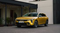 Gelber Kia K4 steht vor einem Gebäude.