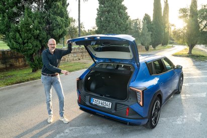 Ein Mann steht vor dem geöffneten Kofferraum des Kia EV4.